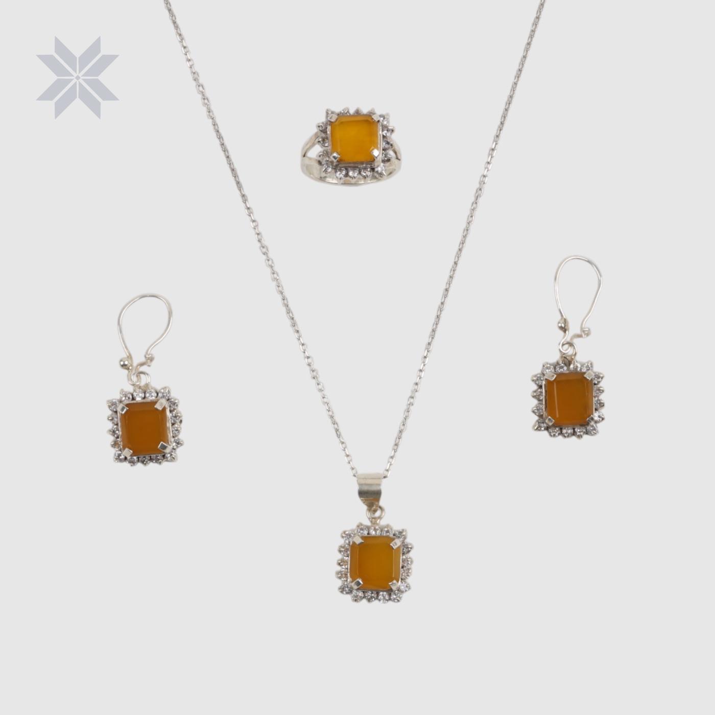 A silver necklace, earrings and ring, each with a square amber stone surrounded by small clear stones.