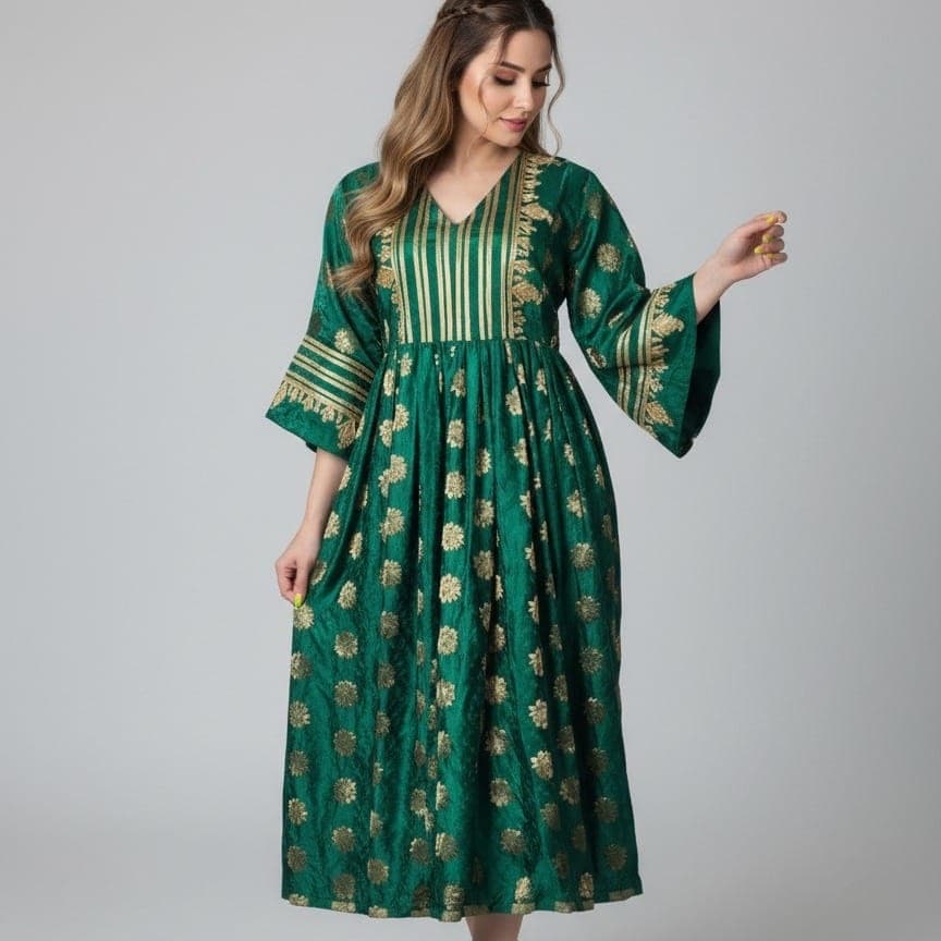A woman in a flowing emerald green dress patterned with gold thread and bell sleeves.