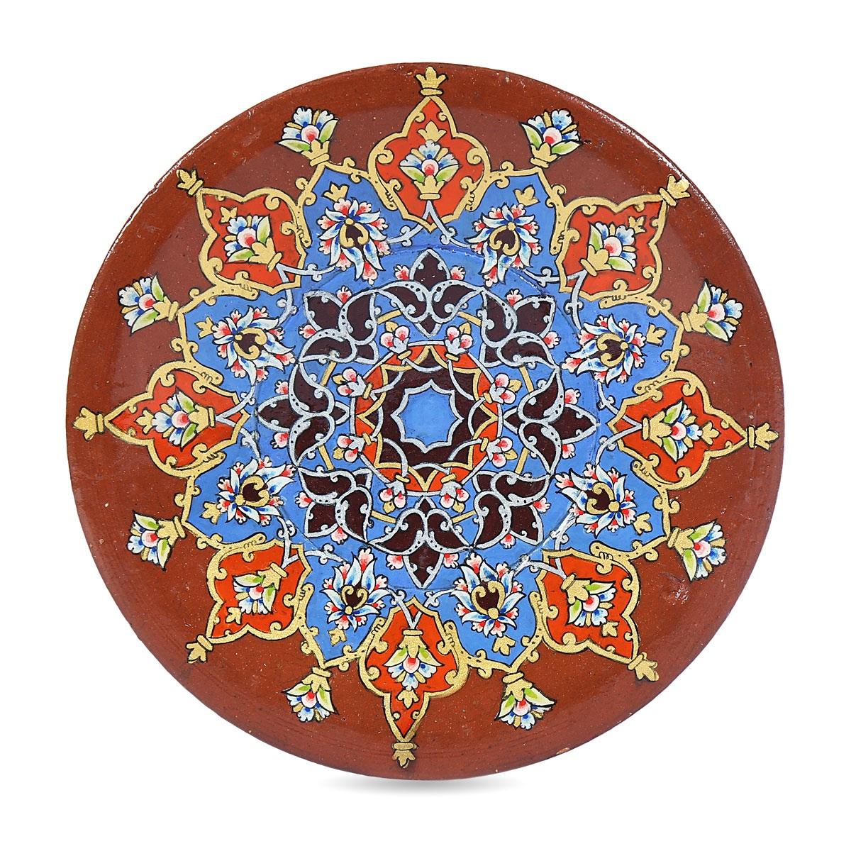 A terracotta plate hand-painted with a large blue, red and gold star medallion.