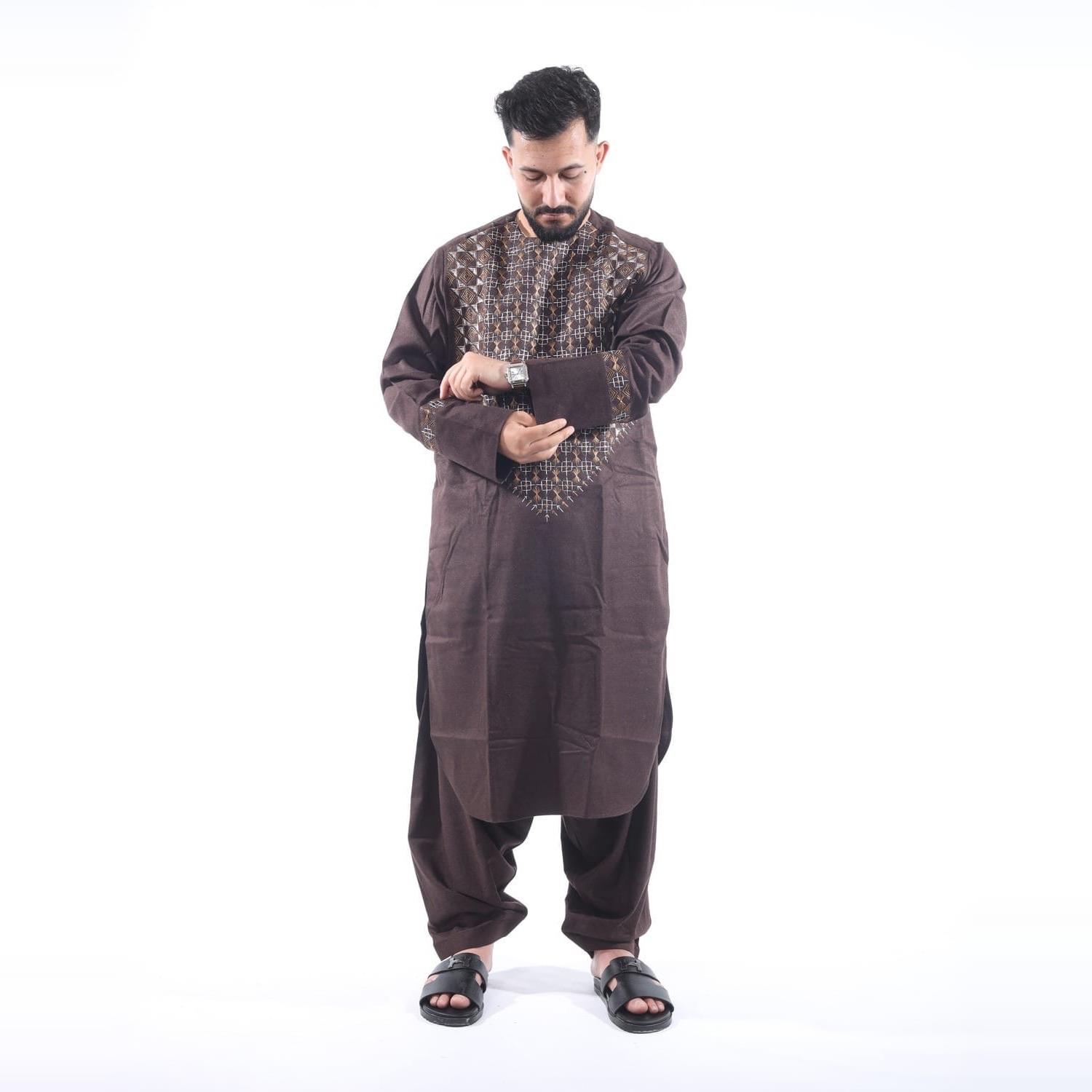 A man in a brown tunic with gold embroidery at the chest, and loose trousers.