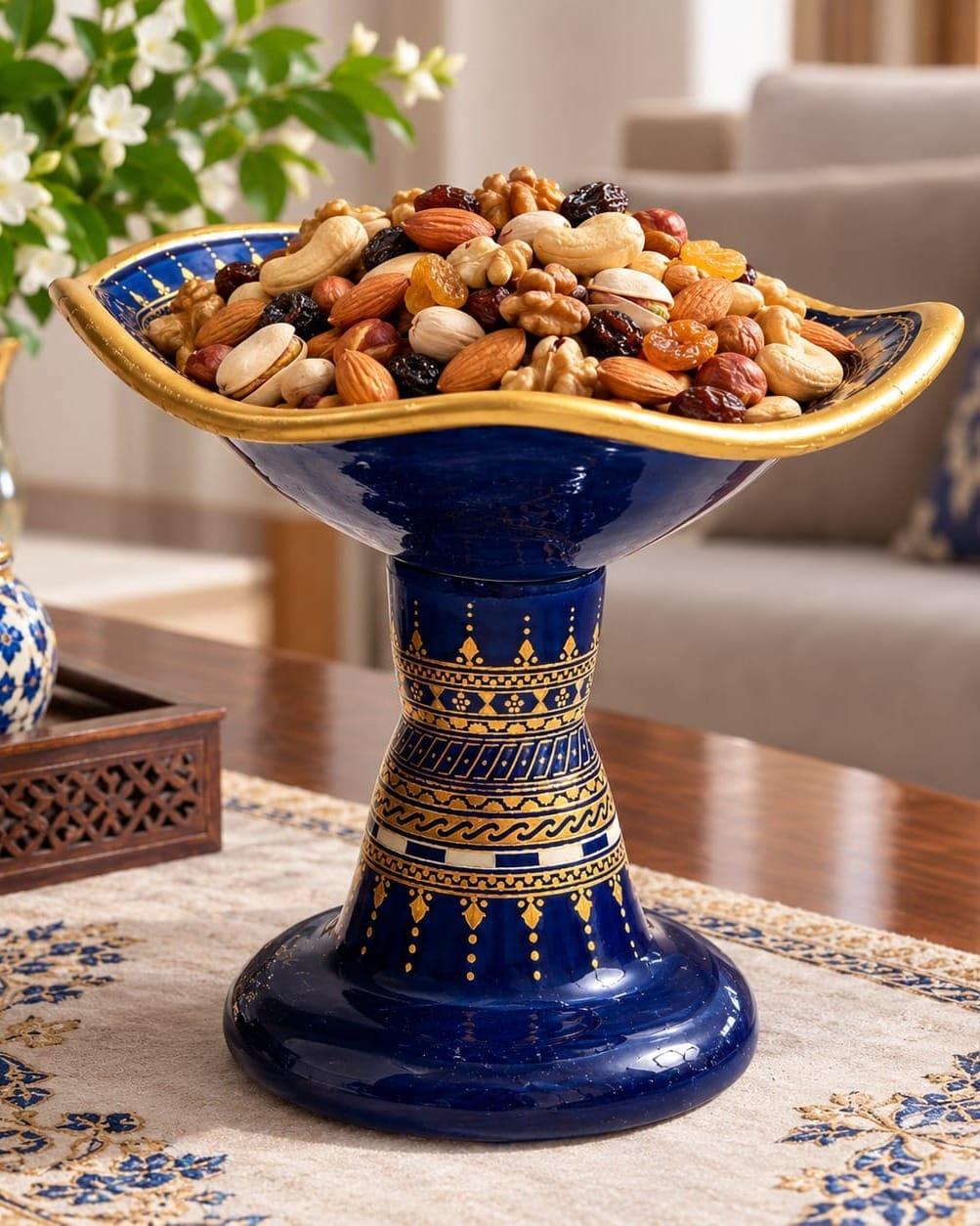 A cobalt blue footed bowl with gold bands, filled with dried fruit and nuts.